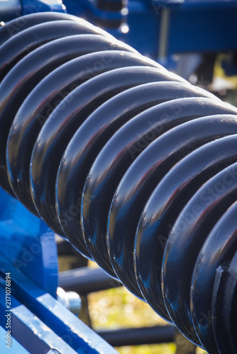 Steel black spring as part of heavy agricultural, industrial machine. Technology