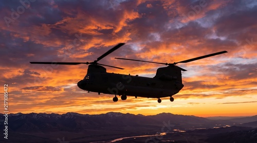 silhouette of military twin-rotor transport helicopter flying over mountains against dramatic fiery sunset sky. aviation and army deployment concept. poster, banner, website header with copyspace.