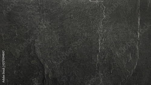 Dark black natural stone surface with subtle cracks, rough texture and weathered details. Abstract slate background with a dramatic charcoal gray pattern.