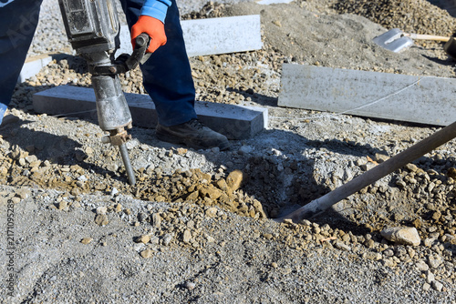 Obraz na płótnie Contractor operates jackhammer on construction site gravel dirt surround work area