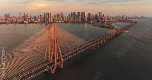 A breathtaking aerial drone view of Mumbai City during the golden evening in the monsoon season, featuring the iconic Bandra-Worli Sea Link stretching across the Arabian Sea.