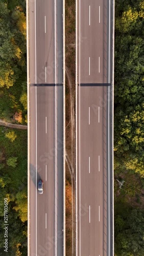 Aerial highway viaduct with cars traveling through a green forest at sunset