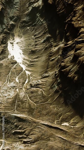 The scene shows a mountain area with distinct river shapes carved into the earth. Light and shadow create a striking display of natural lines. This is viewable from an aerial perspective.