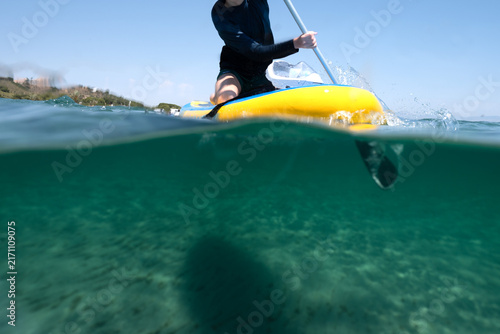 Over-under split shot of a person stand-up paddleboarding in the ocean. 