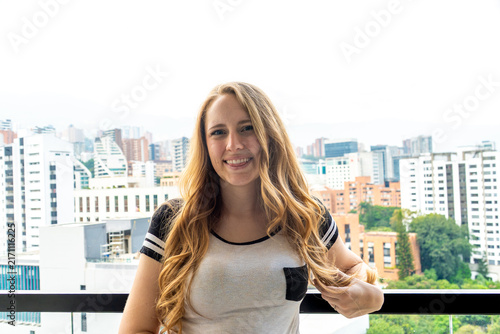 Canvastavla Smiling woman on balcony with city skyline