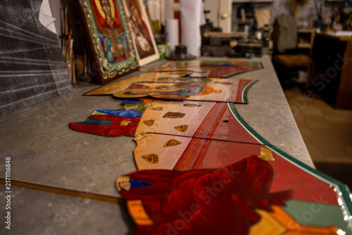 Bild auf Leinwand Orthodox painted icon fragments placed on workbench in art restoration workshop, depicting biblical scenes for church iconostasis manufacturing and preservation