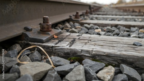 Close-up of train track rail and wooden sleeper with bolts and rocks