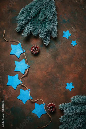 Christmas dark grunge background with blue wooden stars and fir branches, top view, copy space.