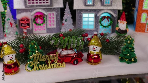 A small and unusual Santa Claus rides in front of a beautiful Christmas town