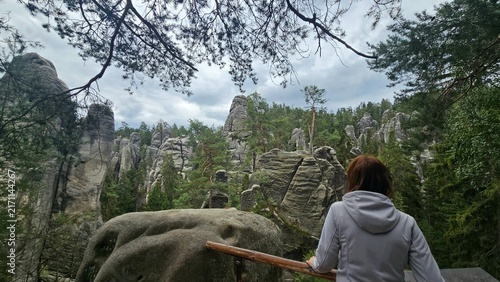 Bild auf Leinwand Female hiker standing on viewpoint looking at sandstone rock pillars and green f
