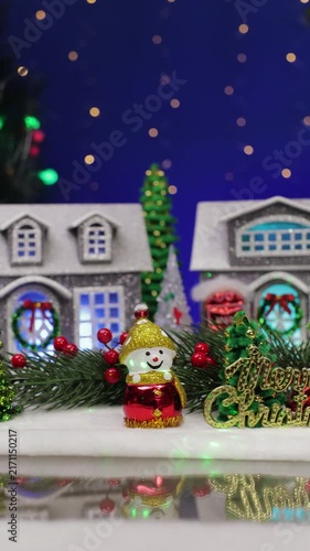 A yellow car with a Christmas tree on the roof enters a Christmas village