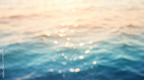 Blurred ocean waves reflect golden sunset light creating a peaceful abstract background texture.