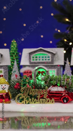 A yellow car with a Christmas tree on the roof drives into a beautiful Christmas town