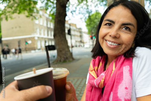 Photography Happy woman smiling in London, enjoying coffee with friend in urban street cafe,