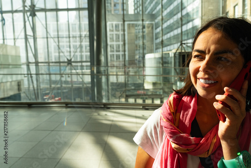 Konstfotografi Woman talking on cellphone in modern airport terminal, connecting and traveling,