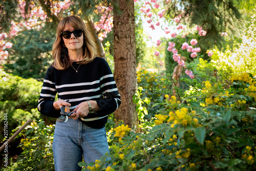 Mid-aged woman and removing old stems and leaves in a back yard