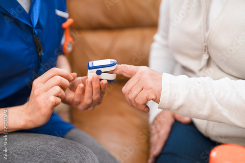 Nurse checks patient's oxygen levels using a pulse oximeter in a home care setting