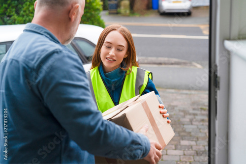 Delivery person hands package to customer at home front door in day time
