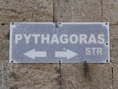 Bild auf Leinwand Weathered vintage blue enamel street sign for Pythagoras Street with white arrows on a historic stone masonry wall