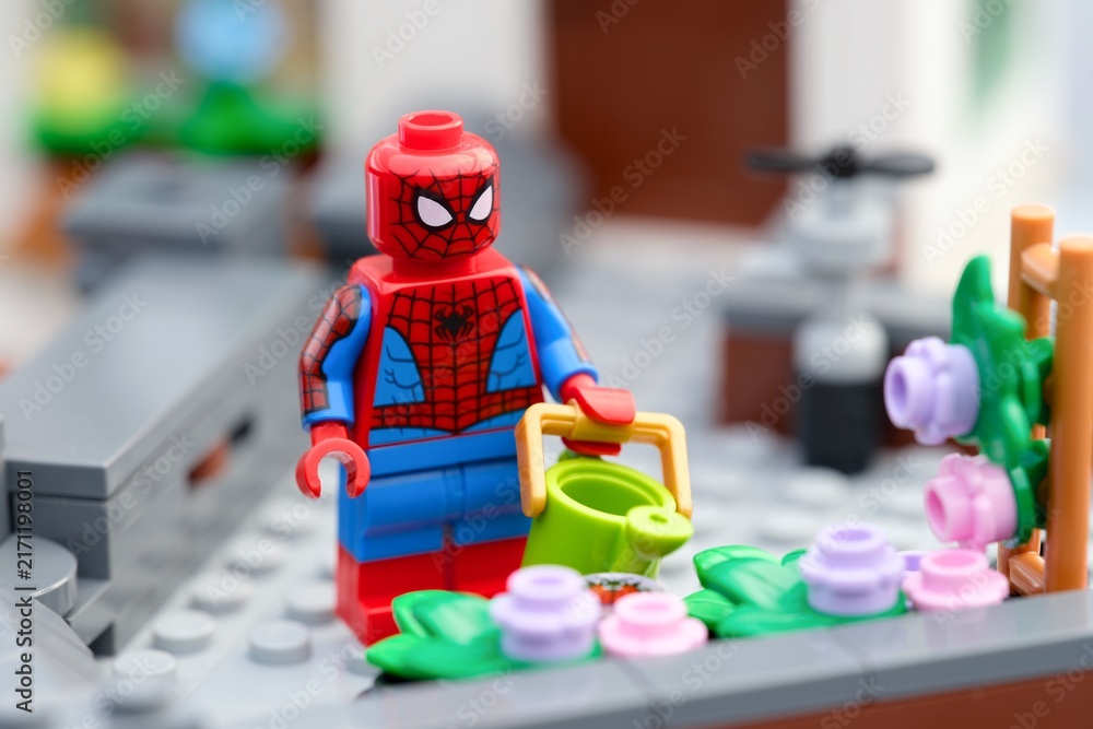 Fototapeta premium Tambov, Russian Federation - August 23, 2026 A Lego Spiderman minifigure with a watering can next to a flower bed on a rooftop garden.