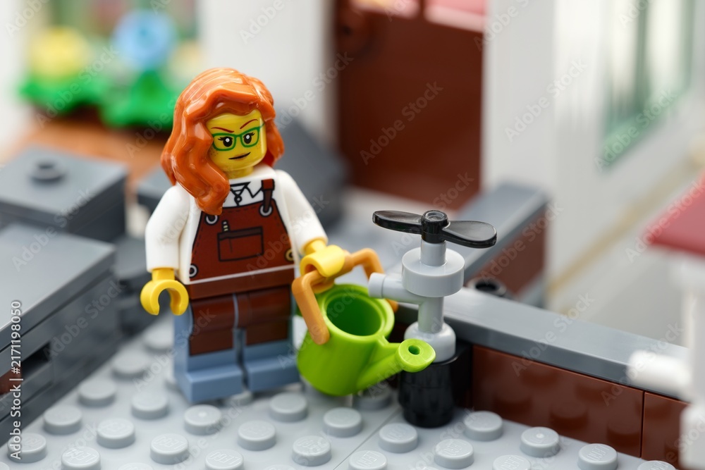 Fototapeta premium Tambov, Russian Federation - August 22, 2026 A Lego woman gardener minifigure with a green watering can next to a water tap.