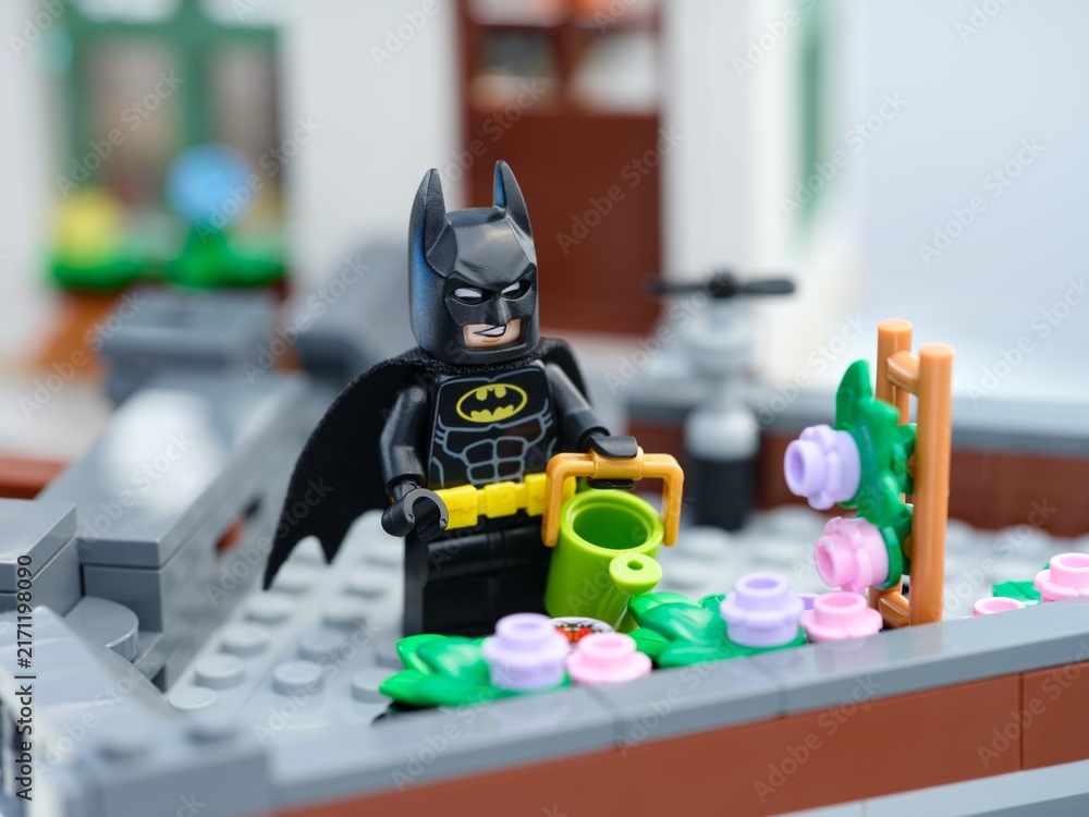 Fototapeta premium Tambov, Russian Federation - August 23, 2026 A Lego Batman minifigure with a watering can next to a flower bed on a rooftop garden.
