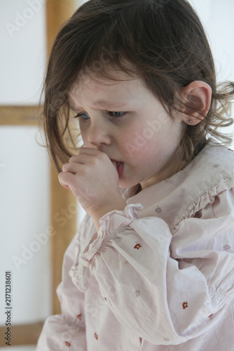 Konstfotografi A closeup of a sad little girl tries to comfort herself by sucking her thumb while feeling upset, sick or emotionally down at home