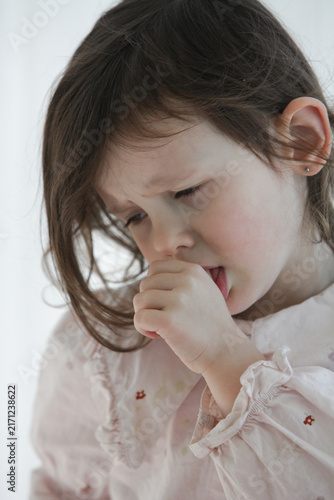 Fotografie A closeup of a sad little girl tries to comfort herself by sucking her thumb while feeling upset, sick or emotionally down at home