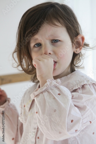 Foto A closeup of a sad little girl tries to comfort herself by sucking her thumb while feeling upset, sick or emotionally down at home