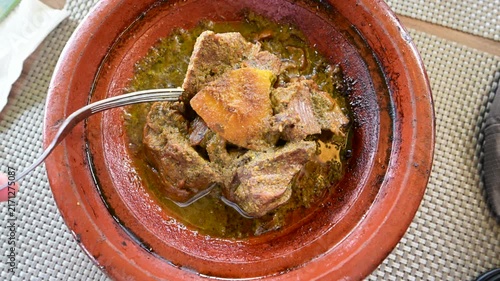 Marrakech, morocco. August 8, 2026. Traditional moroccan lamb tagine steaming in a classic terracotta clay pot. A person uses a fork to eat the tender, slow cooked meat