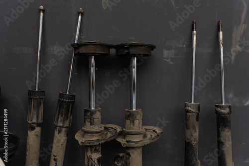 Cuadro en lienzo Used suspension struts and metal components rest in workshop storage against dark wall