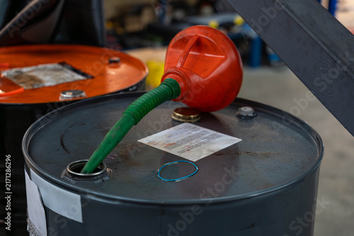Fotografie Industrial oil drum rests in maintenance area with red manual pump green hose fitted into top opening
