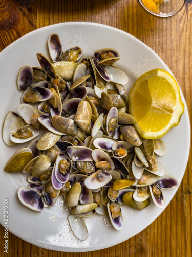 Steamed clams with lemon slice on white plate
