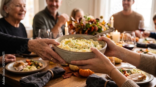 Family sharing a bowl of mashed potatoes at a festive Thanksgiving dinner table with roasted turkey and autumn decorations