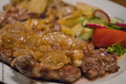 Traditionelles Thüringer Rostbrätl mit geschmorten Zwiebeln, Bratkartoffeln und frischem Salat auf einem Teller, Ziegenrück, Thüringen, Deutschland