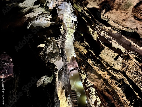 Принти на полотні Illuminated underground cave passage with a subterranean lake, stairs, and massi