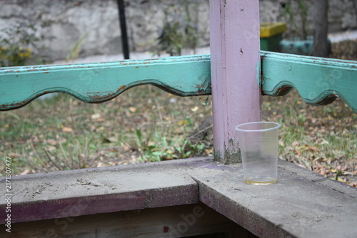 Fotografie An empty transparent plastic glass forgotten on the wooden corner of a children's sandbox at an outdoor park