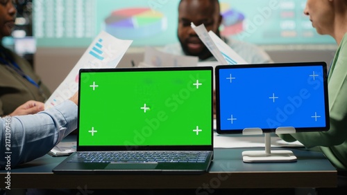 Fotografie Company associates hold an after-hours briefing beside a chroma key screen, exchanging insights to establish project objectives and reviewing a performance summary for goals and presentations