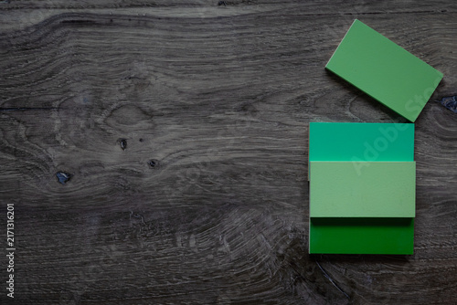 Flat lay background with negative space dark grey wood surface with green wooden tiles.