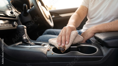 Man wiping spilled liquid from car console with cloth