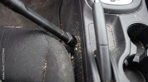 Vacuuming dust and dirt from car center console carpet
