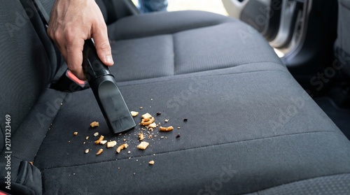 Hand vacuuming food crumbs from car back seat