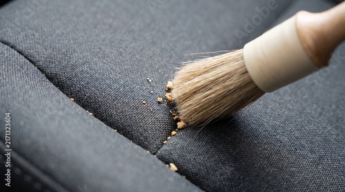 Brushing food crumbs off fabric car seat seam close up