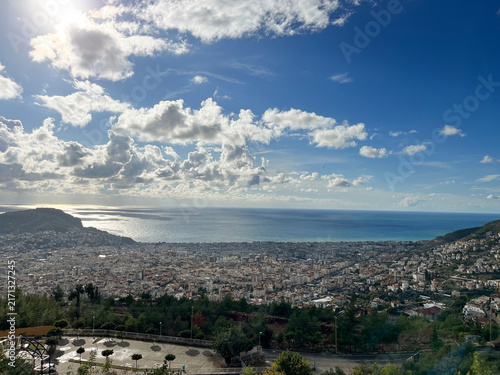 Aerial panoramic view of coastal city with mountains and blue sky with clouds