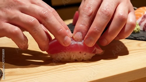 Close-Up Of Sushi Being Expertly Prepared With Hands Shaping Rice And Adding Fresh Tuna In A Professional Kitchen Setting