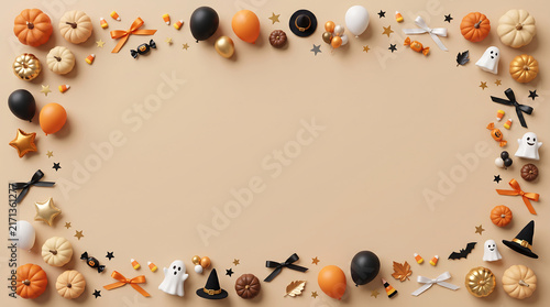 Halloween party border of assorted spooky candy, chocolate, and creepy decorations on neutral background