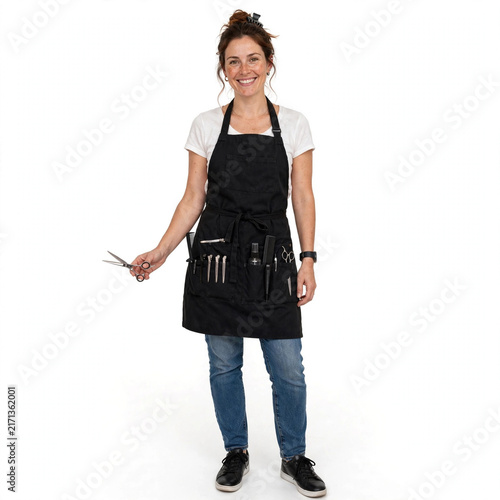 Friendly woman hairdresser wearing black apron holding professional steel scissors for beauty salon.
