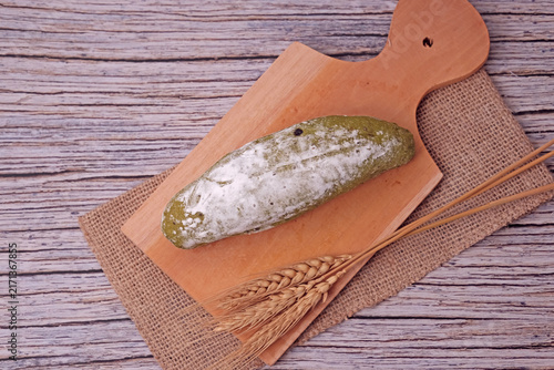 Fresh sourdough dusted with flour rests on wooden board. Golden wheat stalks lie beside it, adding rustic charm. Burlap cloth and warm tones create cozy kitchen ambiance. Perfect for food blogs