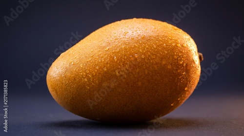 Fresh Ripe Mango Covered with Water Droplets in Dark Studio Rim Lighting
