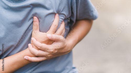 Foto Macro view of a man tightly squeezing his chest shirt showing severe internal pain